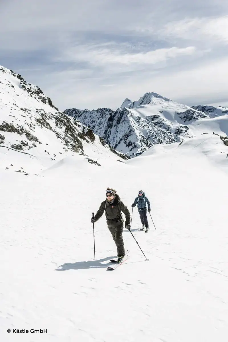 Dos personas andando con su equipo de esquí por la montaña