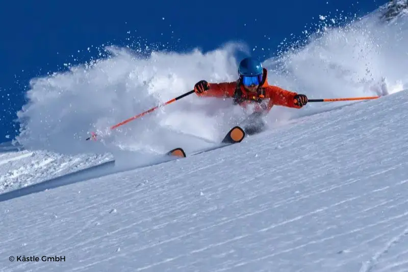 Esquiador deslizándose por la montaña con los brazos extendidos