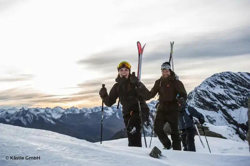 Esquiadores andando por la montaña con puesta de sol