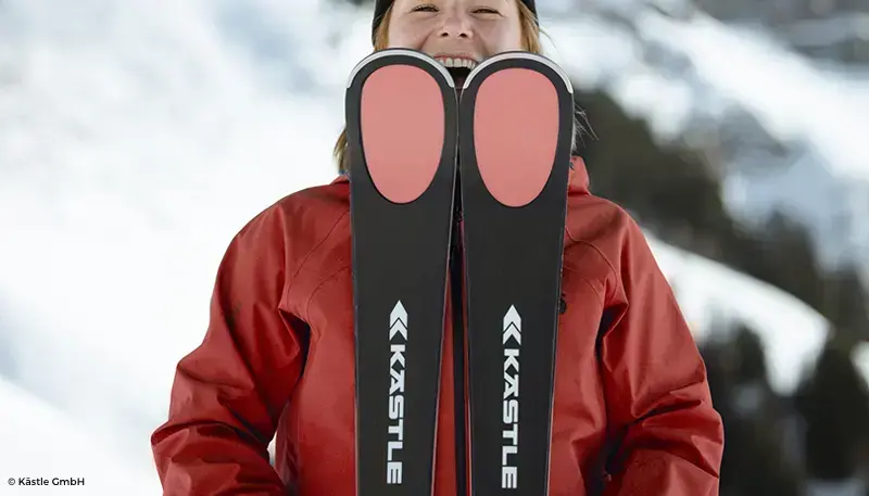 Chica con abrigo rojo y esquís de Kastle