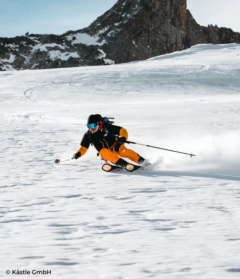 Esquiadora con pantalones naranjas cogiendo una curva